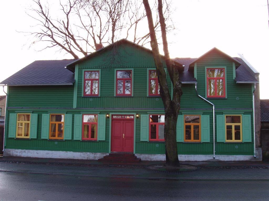 Green wooden hotel with red and yellow windows