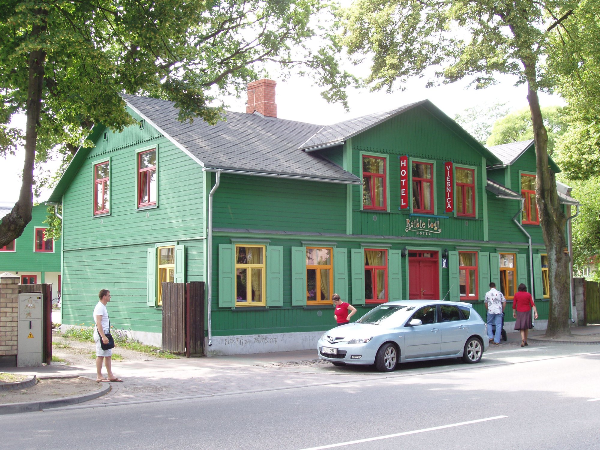 Green wooden facade of Hotel Raibie logi with red and yellow windows in central Ventspils